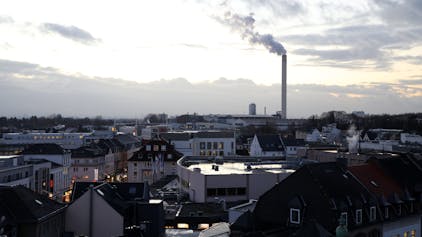 Die Innenstadt von Bergisch Gladbach, im Hintergrund ein qualmender Fabrikschornstein
