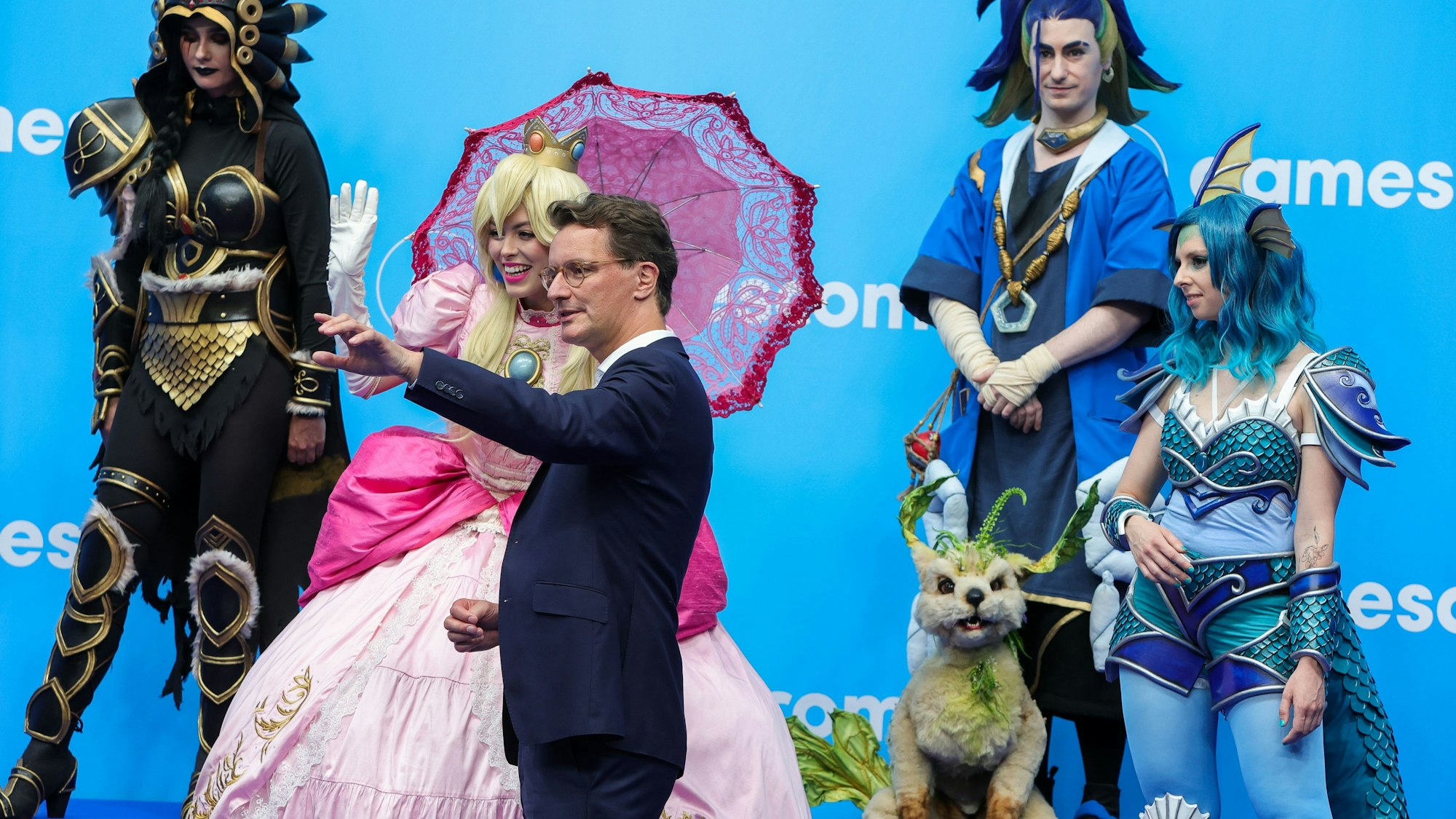 Hendrik Wüst (CDU), Ministerpräsident von Nordrhein-Westfalen, spricht mit verkleideten Spiele-Charakteren auf der Gamescom 2023.