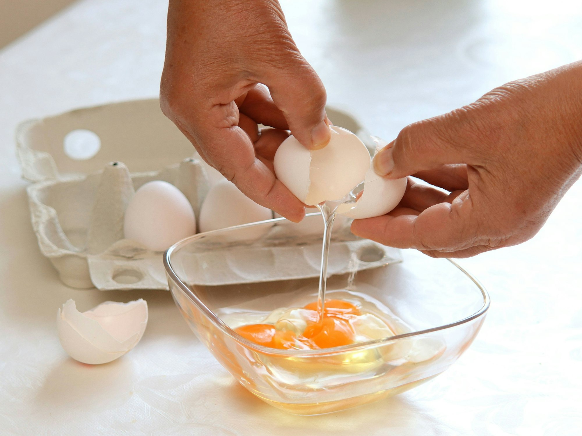 Eine Frau schlägt Eier in eine Schüssel auf.