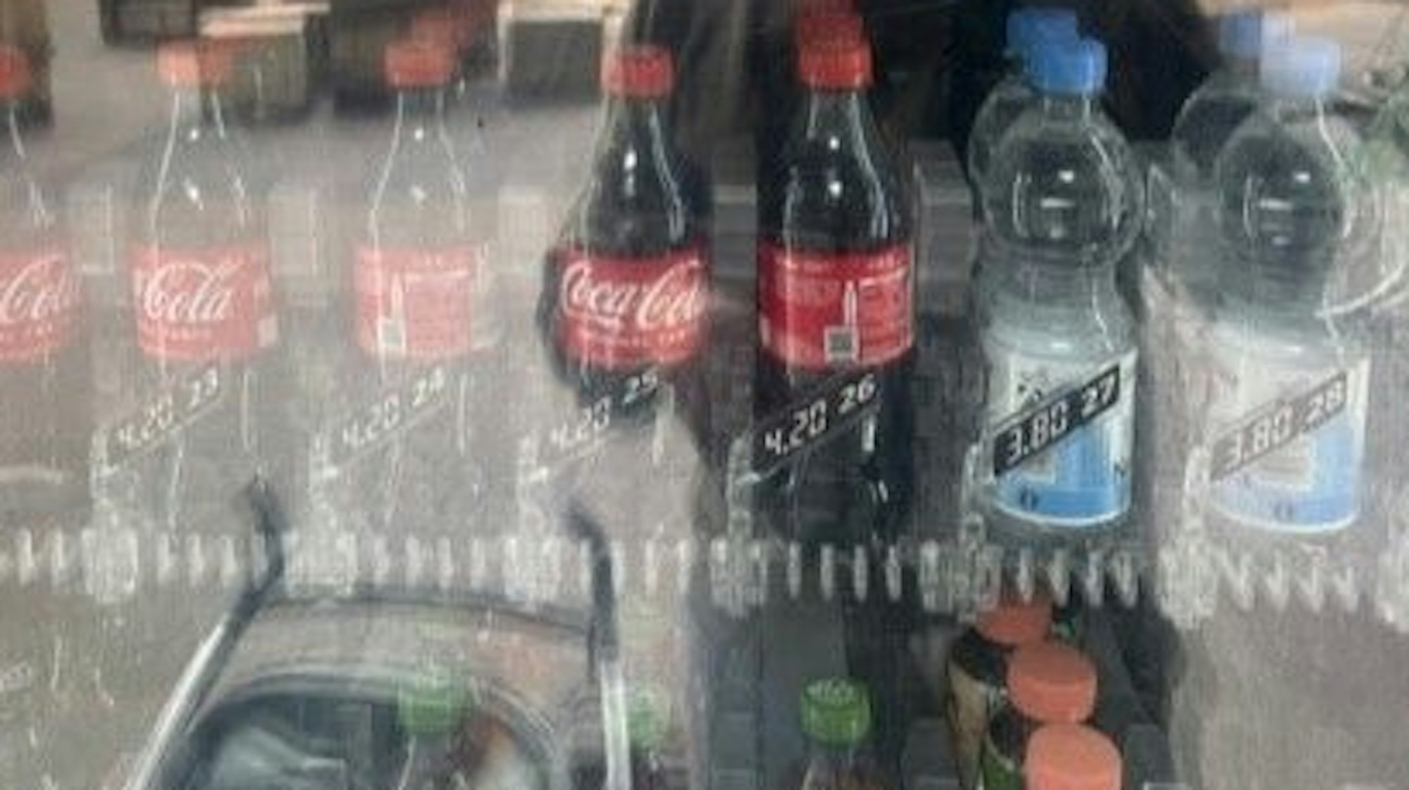 Blick in einen Getränkeautomaten, es sind Cola- und Wasserflaschen zu sehen.