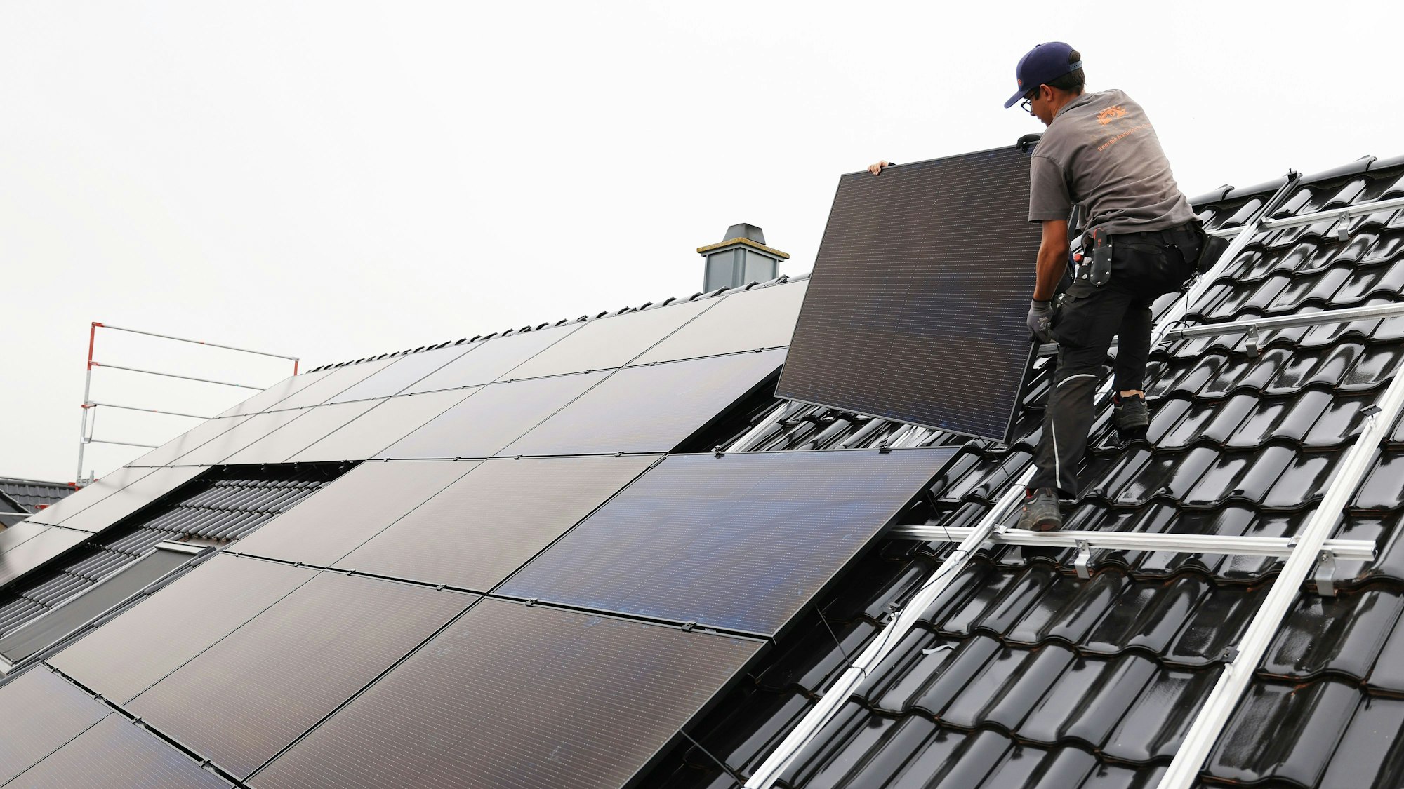 Handwerker montieren auf dem Dach eines Wohnhauses Solarmodule.