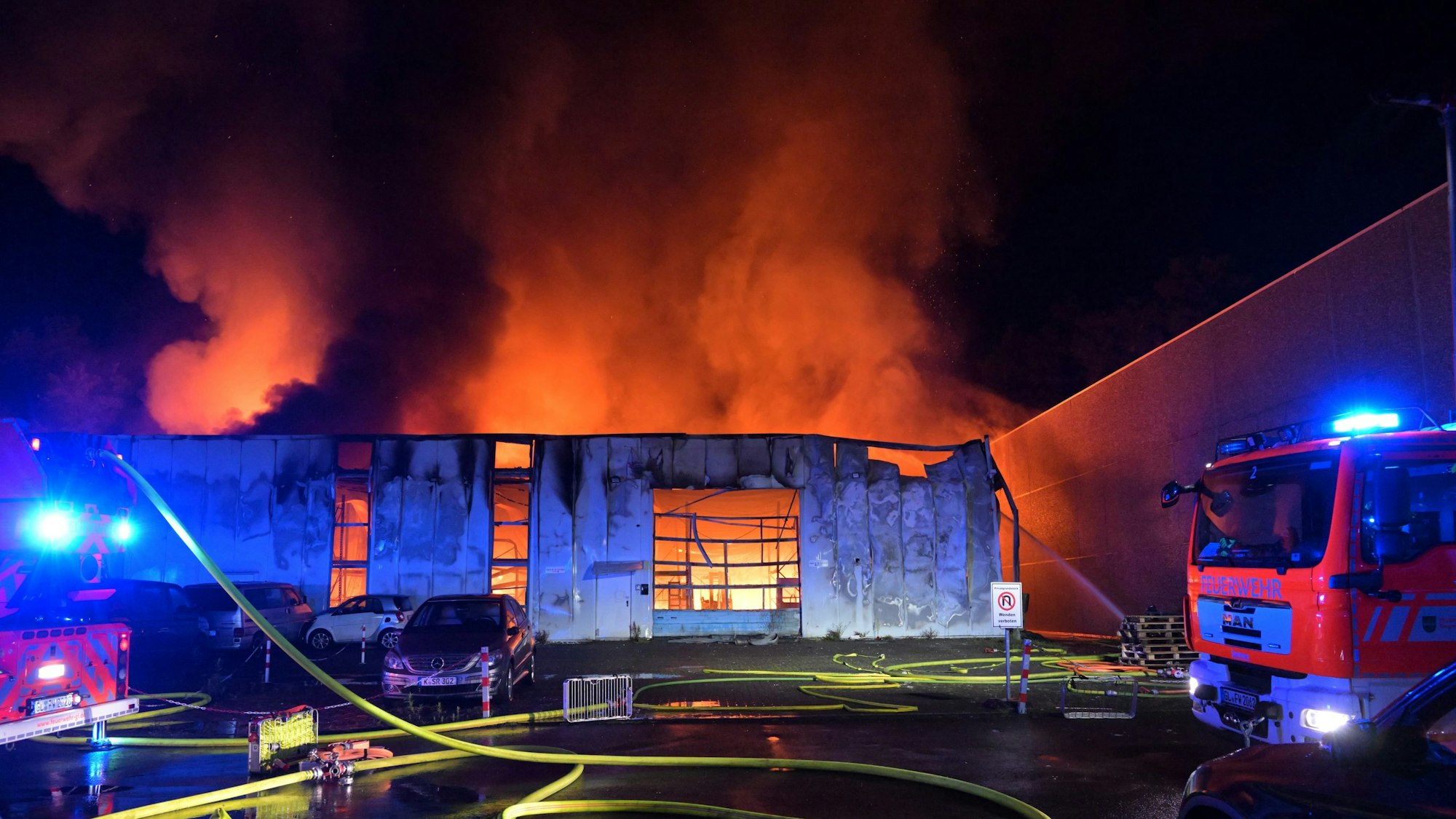 Feuerschein ist in einer Lagerhalle zu sehen, die durch einen Brand bereits stark beschädigt ist.