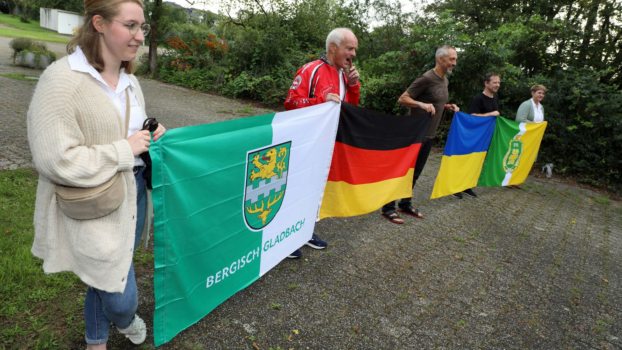 Menschen halten Fahnen von von Ukraine, Deutschland, Butscha und Bergisch Gladbach in den Händen.