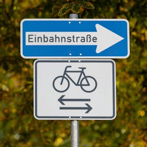 Das Bild zeigt ein Einbahnstraßen-Schild. Darunter: eine Abbildung eines Fahrrads. Pfeile zeigen in beide Richtungen.