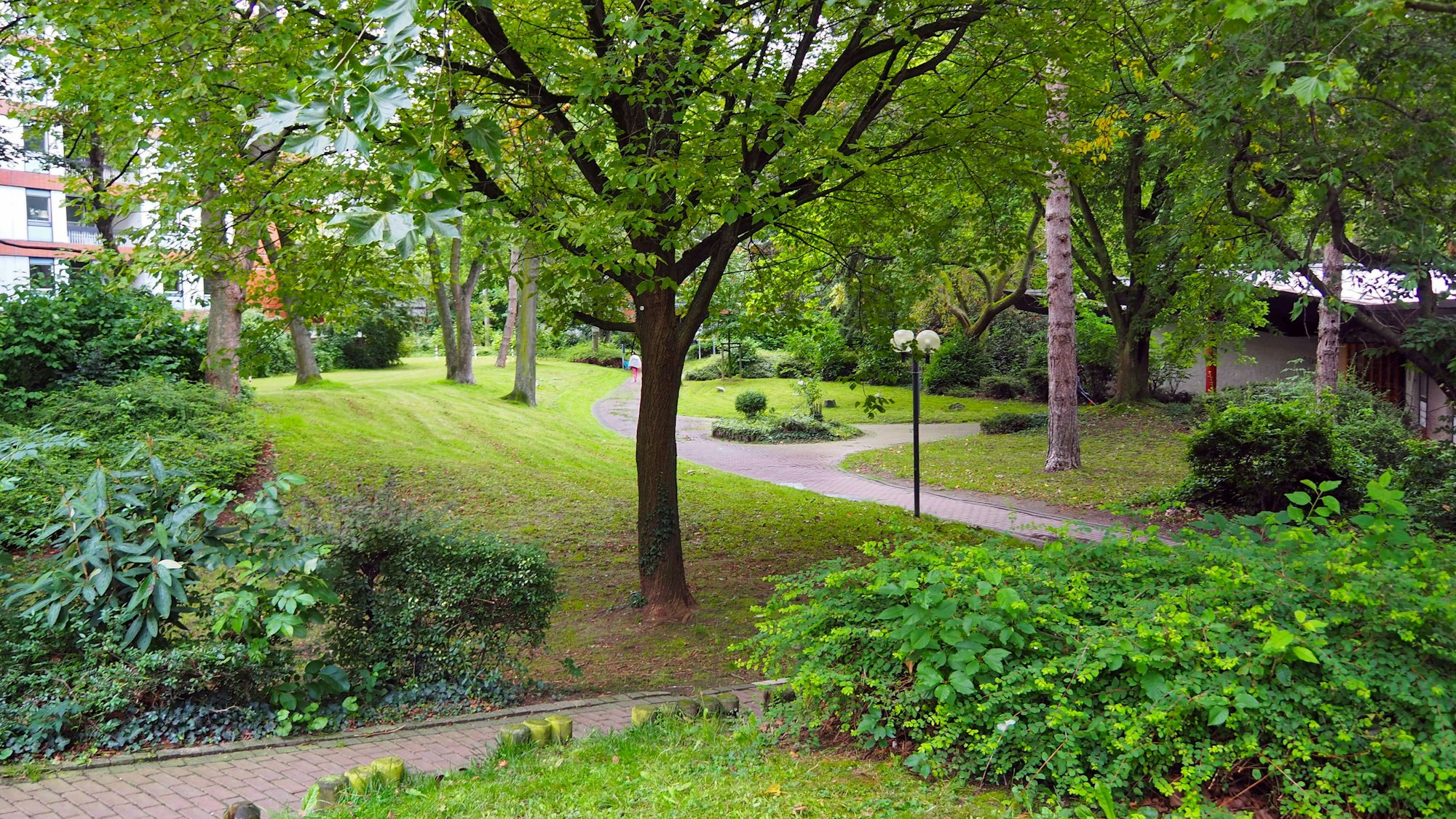 Ein gepflegter Park mit Bäumen und Wegen ist zu sehen.