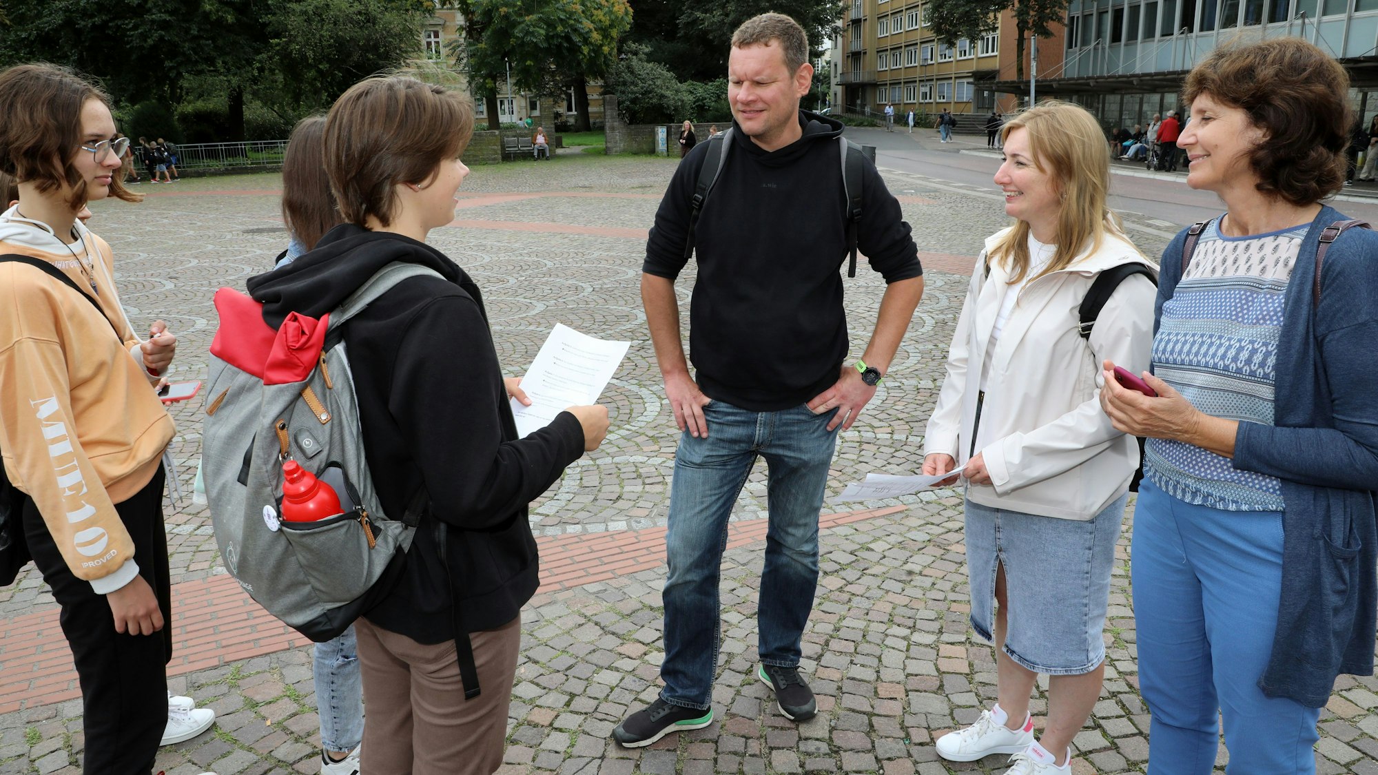 Schüler und Lehrer stehen bei einer Stadtrallye auf dem Konrad-Adenauer-Platz in der Bergisch Gladbacher Stadtmitte.