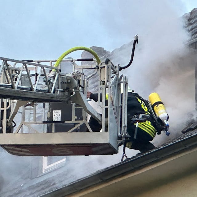 Eine Einsatzkraft der Feuerwehr auf dem Dach des Mehrfamilienhauses in Dünnwald.