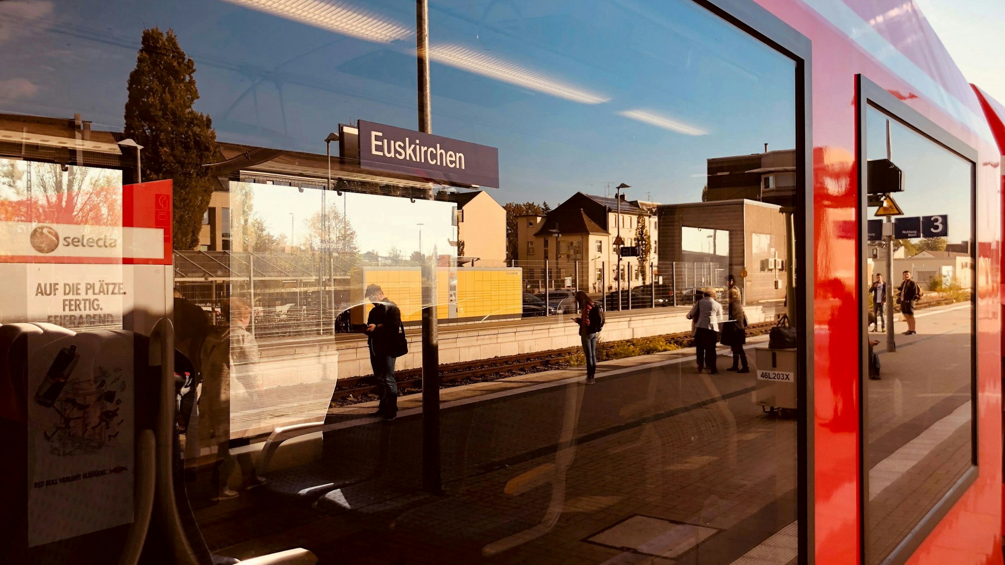 In den Fenstern eines Nahverkehrszuges spiegelt sich der Euskirchener Bahnhof.