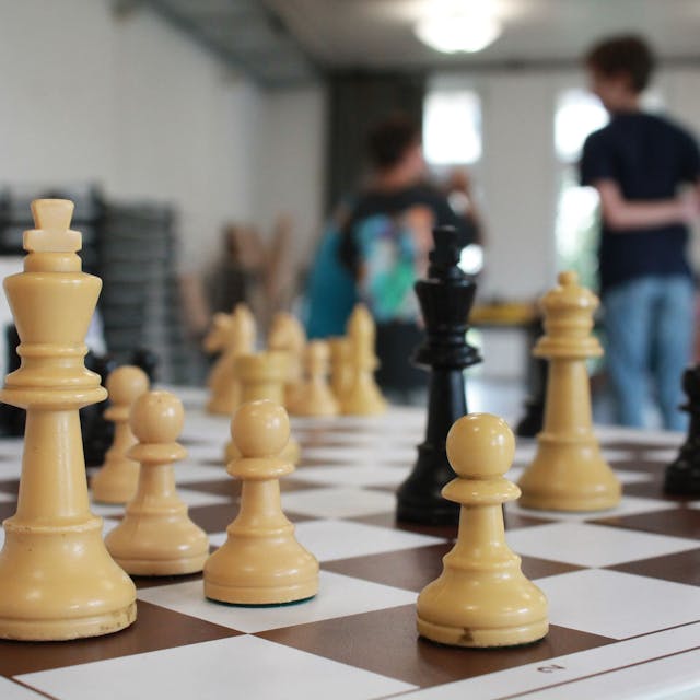 Ein Schachbrett, im Hintergrund Jugendliche