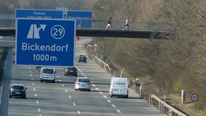 Auf der Stadtautobahn A57 fahren Autos. Ein blaues Schild zeigt die Ausfahrt 29 nach Bickendorf in 1000 Metern an.