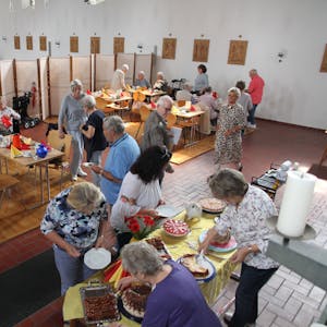 Gäste bedienen sich an einem Kuchenbuffet in einer Kirche.