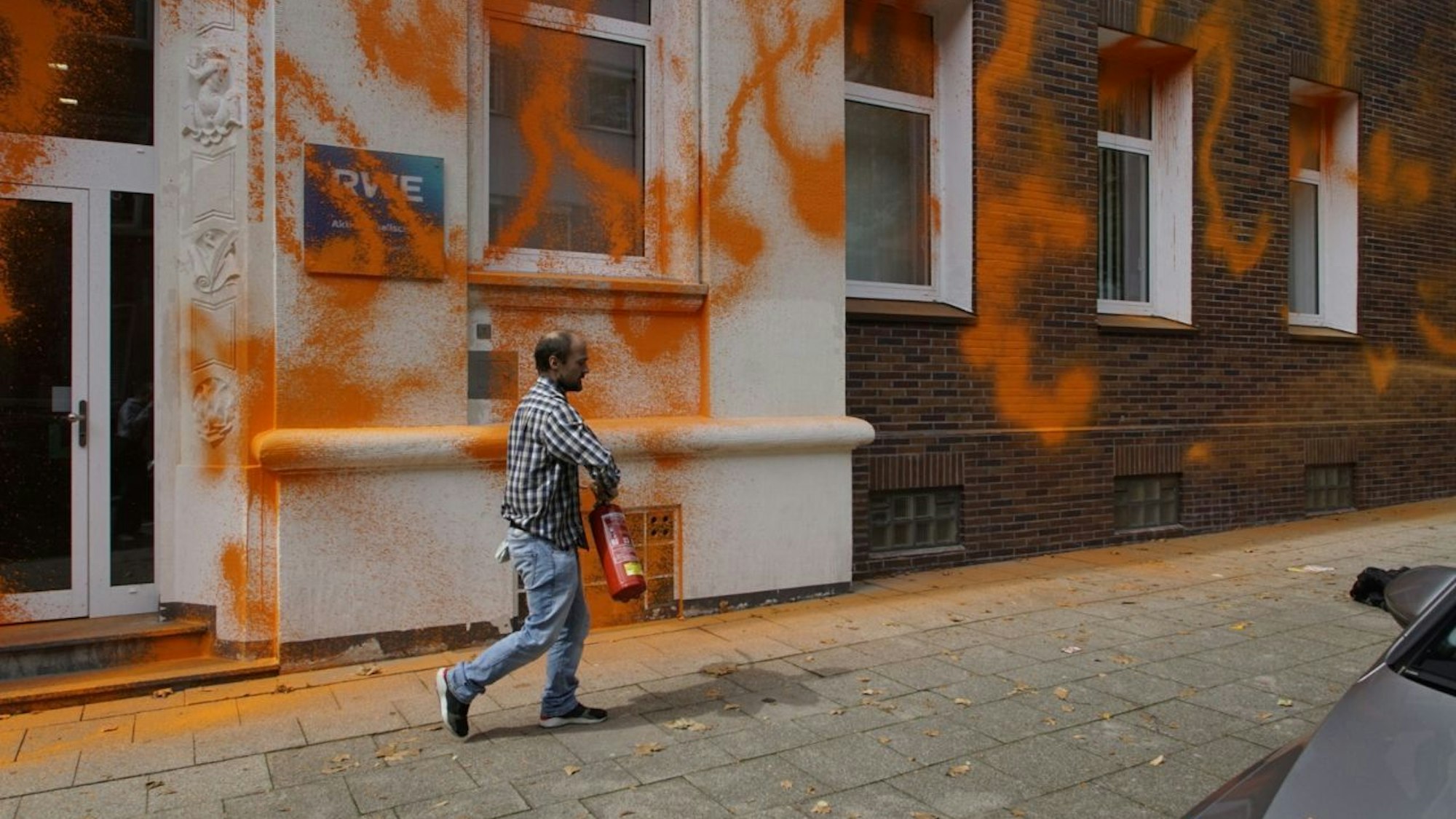 Ein Mann mit Feuerlöscher hat die Front der RWE-Zentrale in Essen mit orangener Farbe beschmiert.