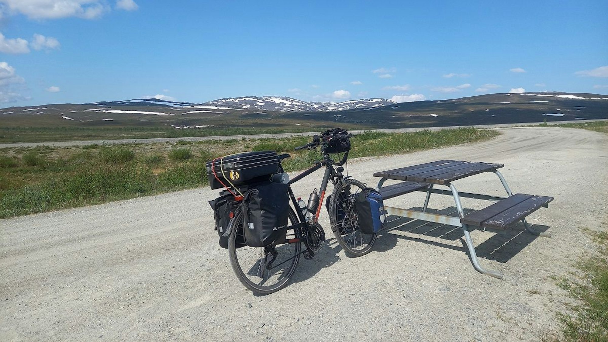 Ein Fahrrad steht an einer Bank in einer weitläufigen Landschaft.