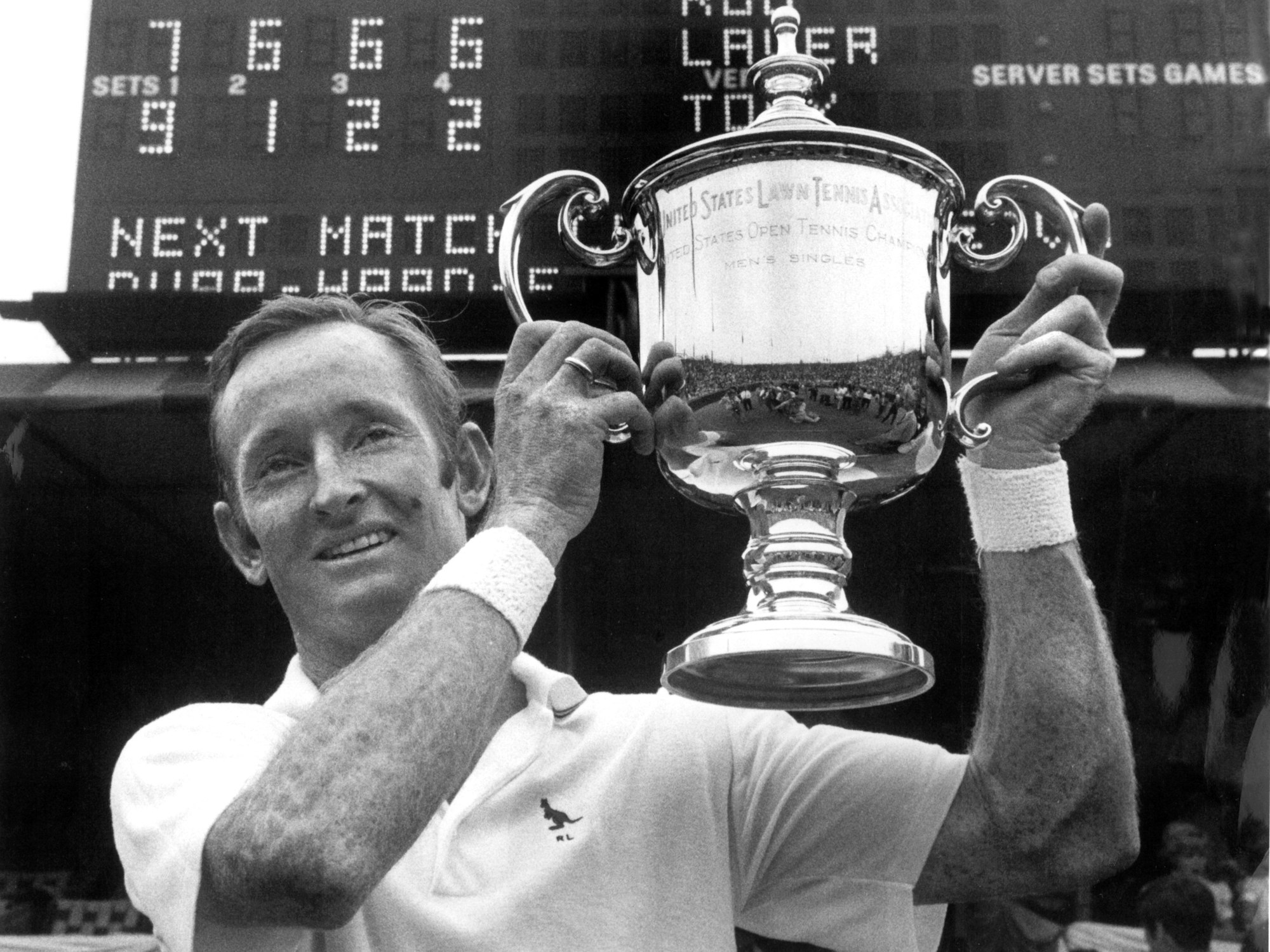 Der australische Tennisspieler Rod Laver hält lächelnd den Pokal in den Händen, der ihm als Sieger der US-Open überreicht wurde.