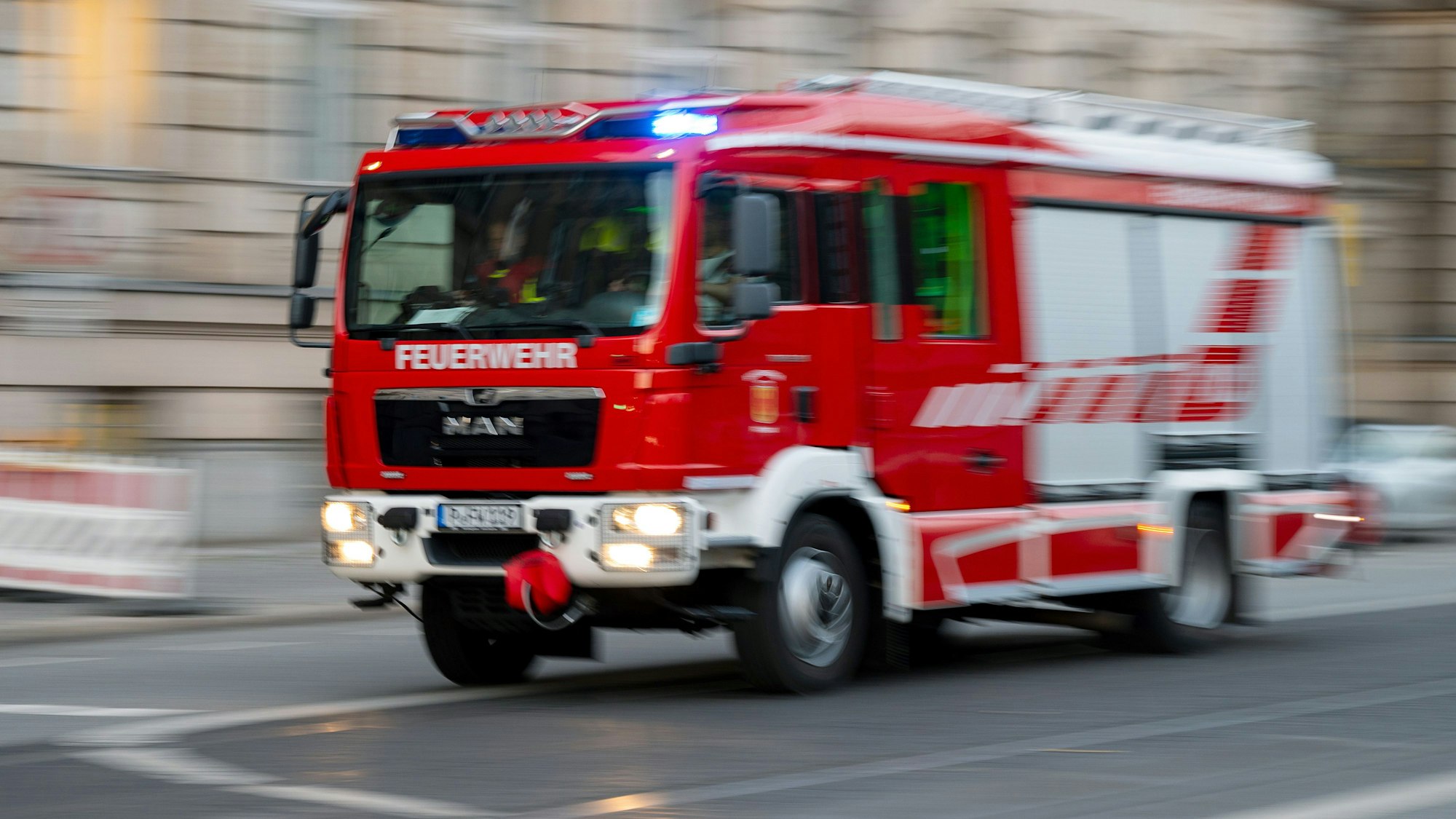 Ein Feuerwehrauto mit eingeschaltetem Blaulicht fährt zu einem Einsatz. In Köln-Mülheim hat es in der Nacht auf Mittwoch gebrannt. (Symbolbild)