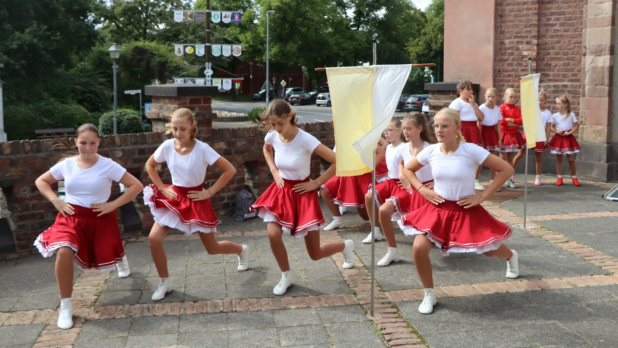 Mädchen in roten Röcken tanzen vor der Kirche.