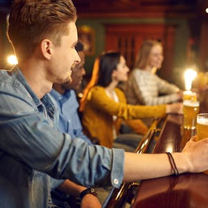 Junge Menschen sitzen in einer Bar und trinken Bier. (Symbolbild)