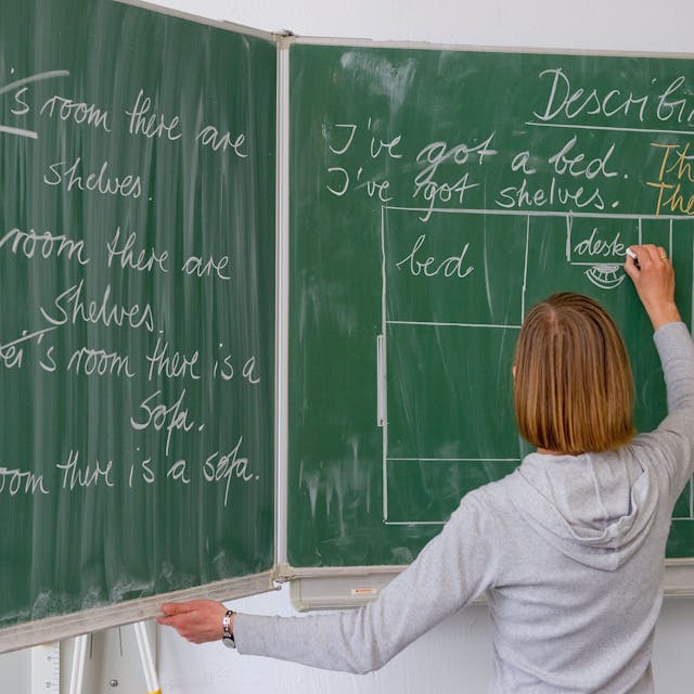 Eine Englisch-Lehrerin einer Grundschule schreibt Unterrichtsinhalte an die Tafel.