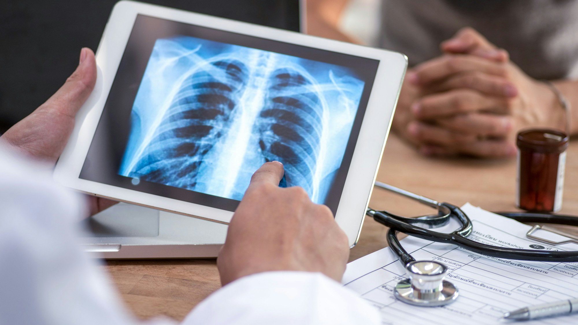Ein Arzt liest den Lungen-Scan auf einem digitalen Tablet-Bildschirm.