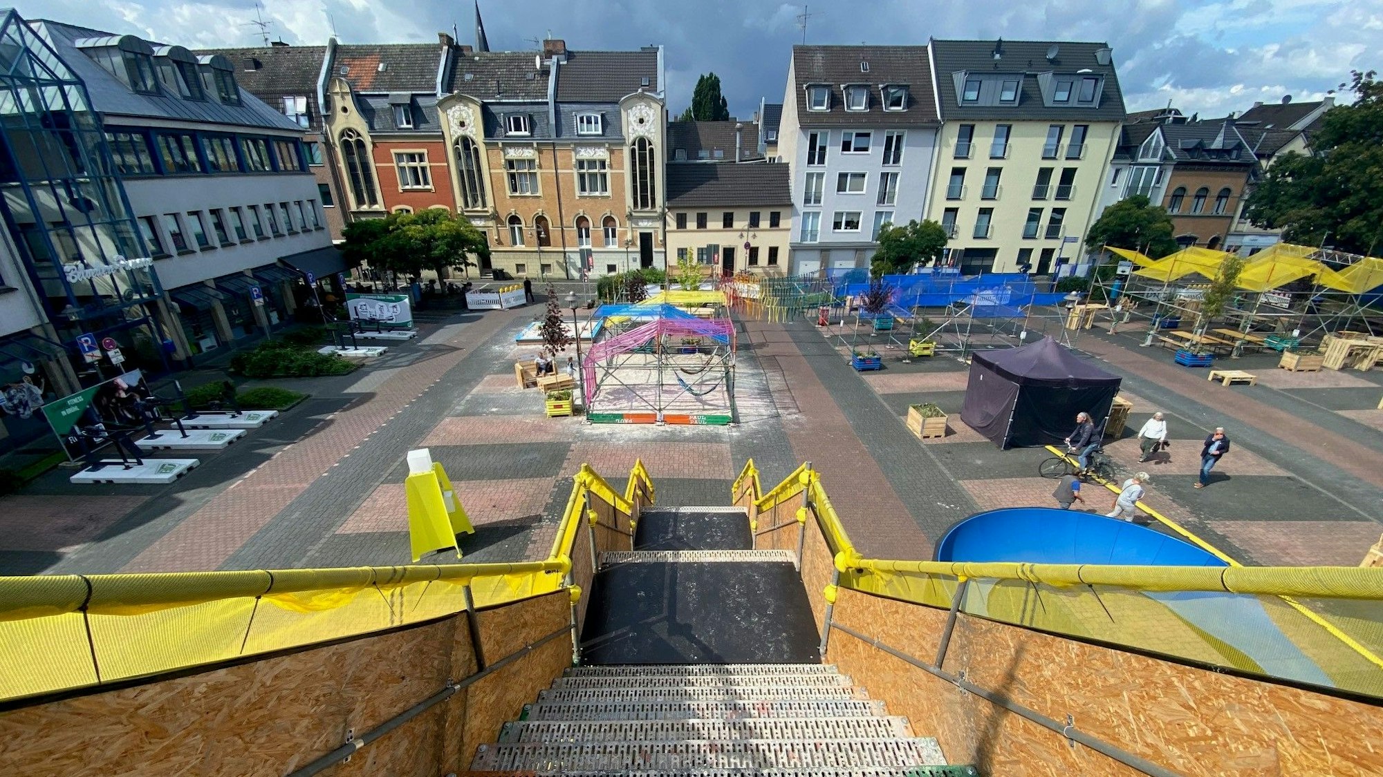 Das Bild zeigt den Belvedere-Platz aufgenommen von einer dort aufgebauten Aussichtsplattform. Zu sehen sind Sitzgelegenheiten und Sportgeräte sowie die Häuser rund um den Platz.