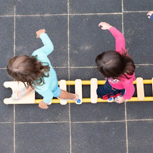 Kinder balancieren auf dem Spielplatz einer Kindertagesstätte auf einem Brett.&nbsp;