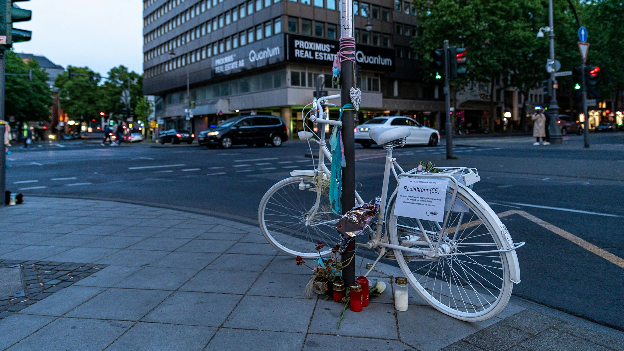 Weißes Fahrrad mit Blumen und Kerzen steht als Mahnmal in der Kölner Innenstadt.