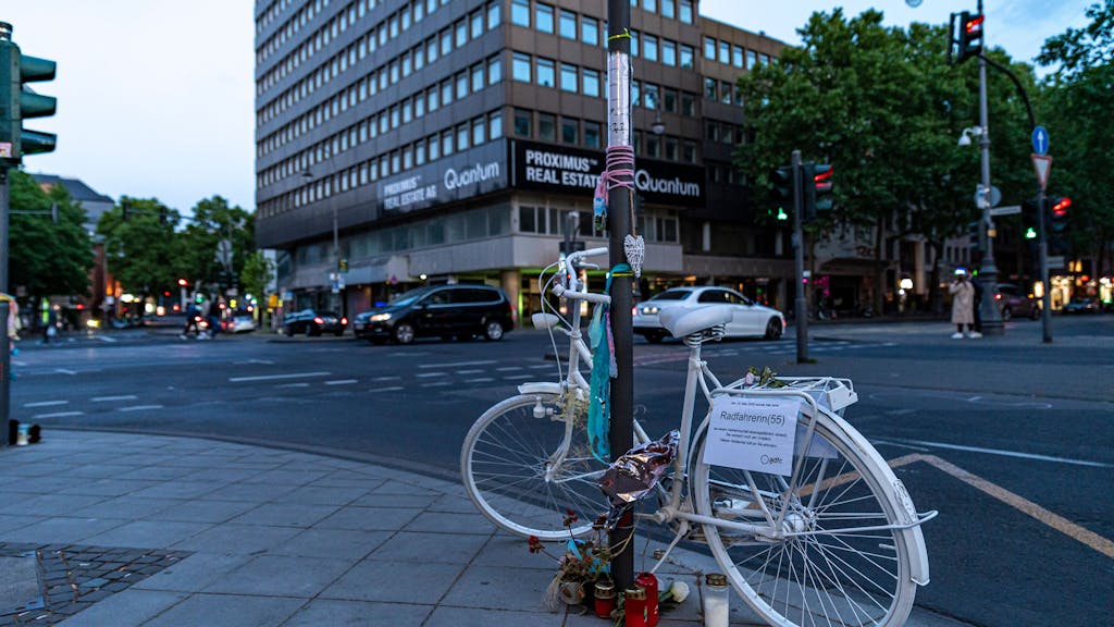 Weißes Fahrrad mit Blumen und Kerzen steht als Mahnmal in der Kölner Innenstadt.