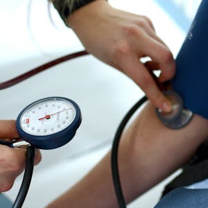 Einem Menschen wird in einer Arztpraxis der Bluthochdruck gemessen.