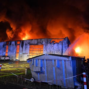 Flammen schlagen aus dem Dach einer Gewerbehalle.