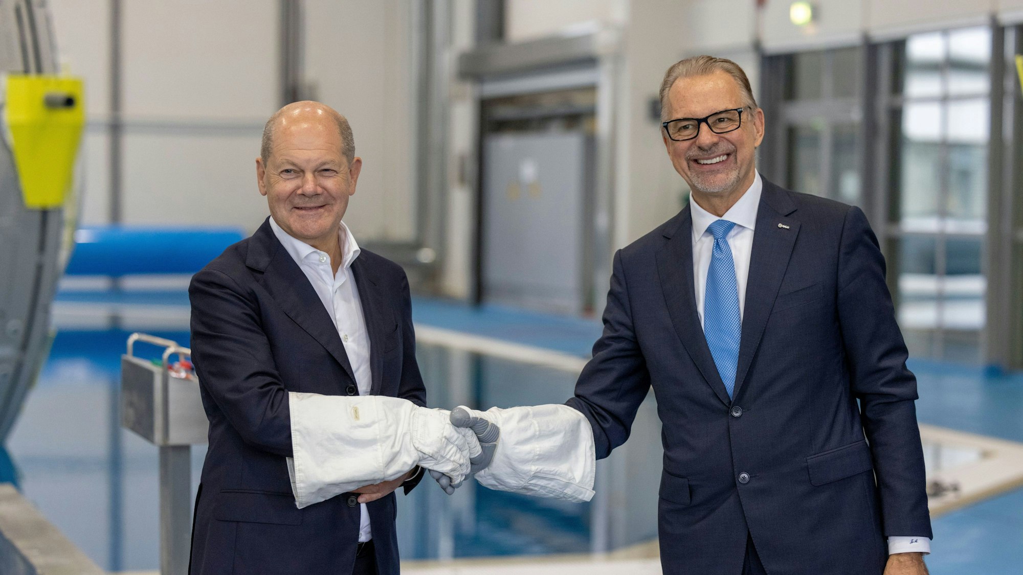 Mit Astronautenhandschuhen gaben sich Bundeskanzler Olaf Scholz (l, SPD) und ESA-Generaldirektor Dr. Josef Aschbacher die Hand während seines Besuchs des Deutschen Zentrum für Luft- und Raumfahrt (DLR) und des Astronautenzentrums der Europäischen Weltraumorganisation ESA.