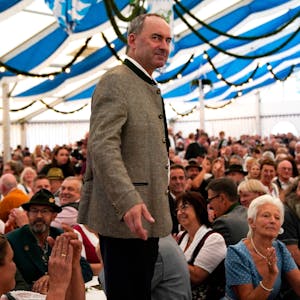Der bayrische Wirtschaftsminister Hubert Aiwanger steht auf einer Bühne in einem Festzelt in blau-weißen Farben.