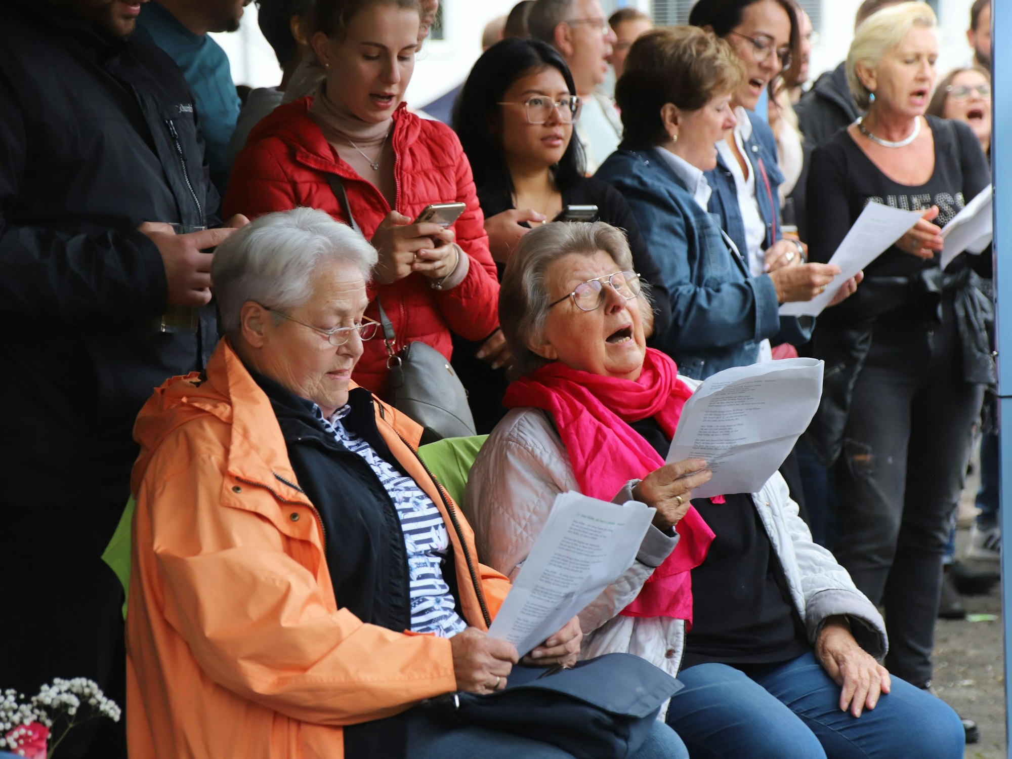 Die Besucher des Mitsingkonzerts haben Textblätter in den Händen und singen die Lieder mit.