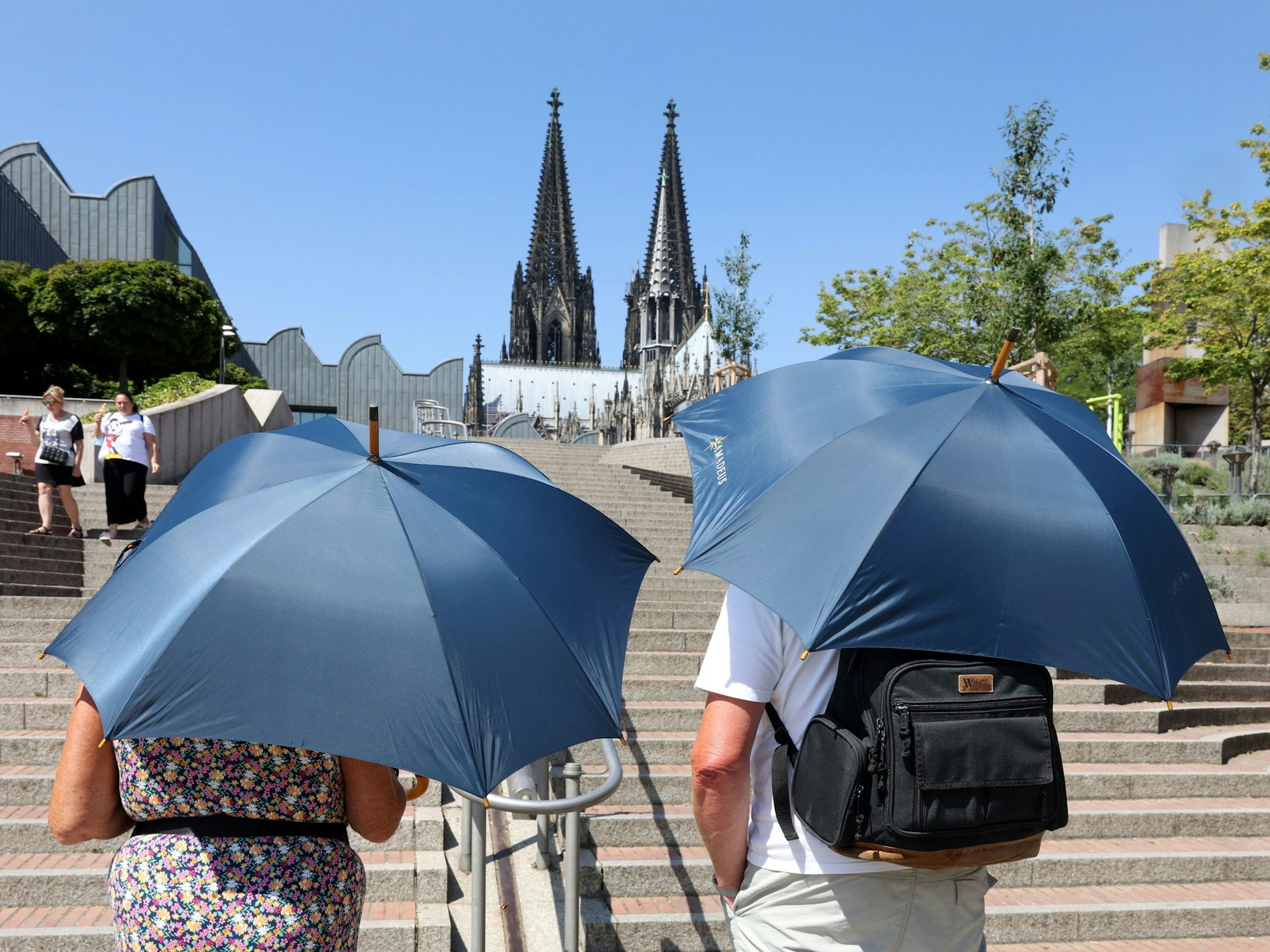 Zwei Touristen mit Regenschirmen als Sonnenschirme