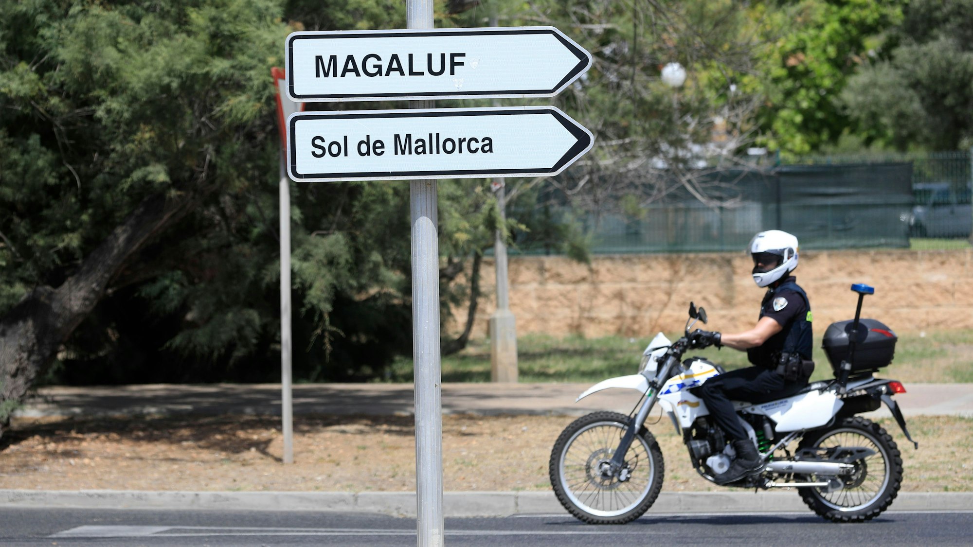Ein Polizist fährt an einem Wegweiser zu Magaluf und Sol de Mallorca vorbei.