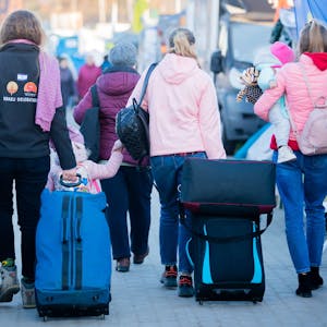 Frauen und Kinder, die aus der Ukraine geflohen sind, werden am Grenzübergang kurz hinter der ukrainischen Grenze, auf polnischer Seite, von einer freiwilligen Helferin (l.) begleitet. (Symbolbild)