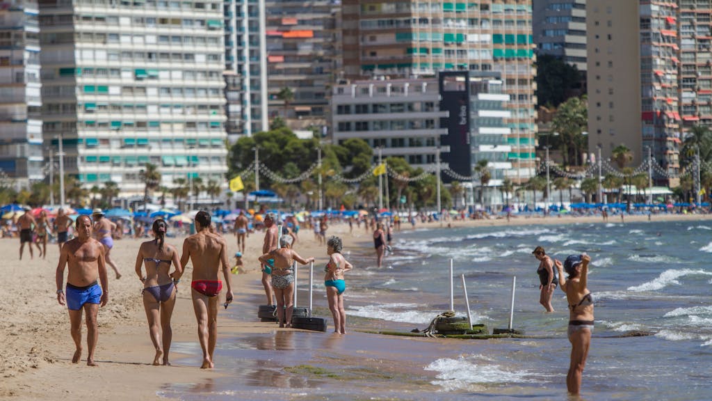Menschen in Badekleidung an einem Strand in Spanien.