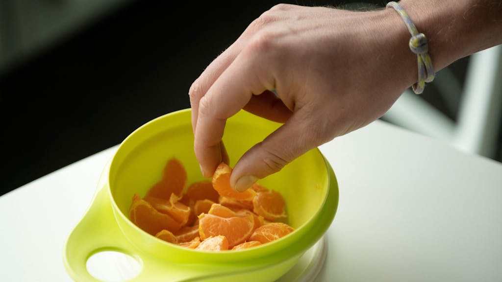 Mandarinen-Stücke in einem grünen Tupperware-Behälter.
