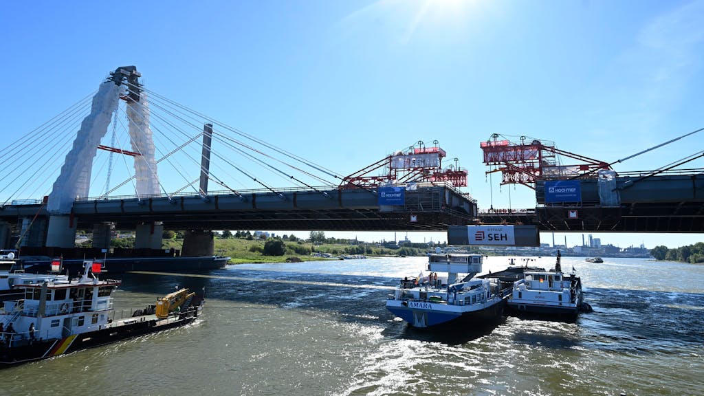 Ein Kran hebt das letzte Bauteil zur Brückenhochzeit an den Neubau der Leverkusener Rheinbrücke.