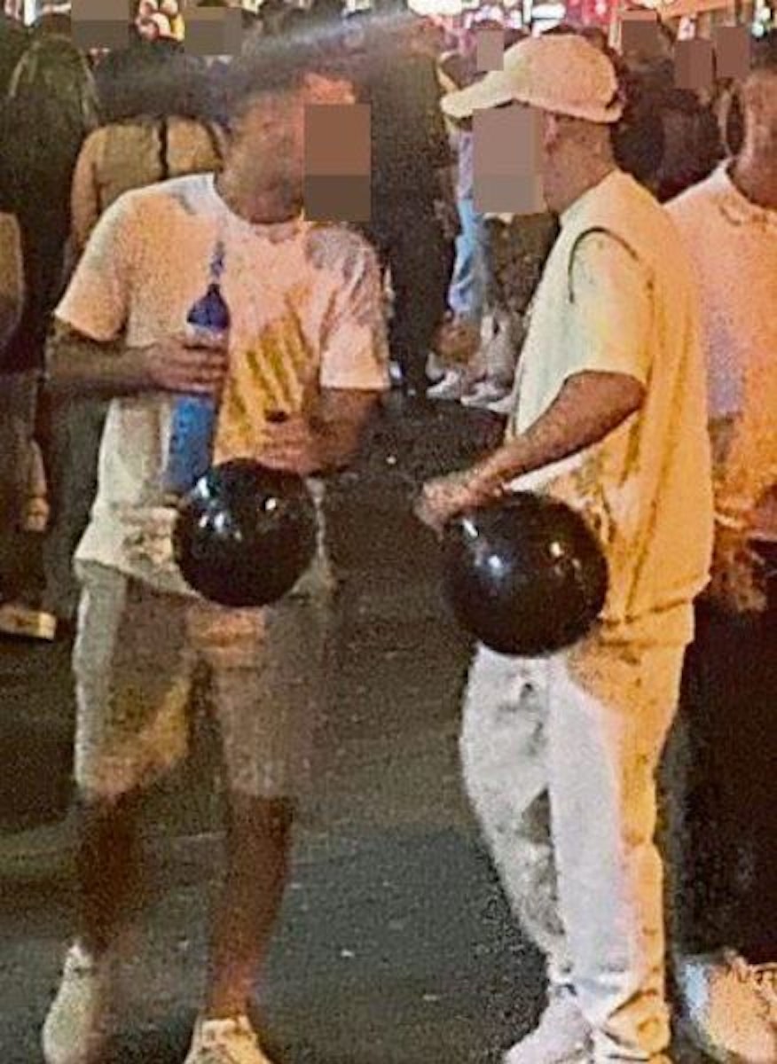 Zwei Männer stehen mit Lachgas-gefüllten Luftballons auf einer Straße.