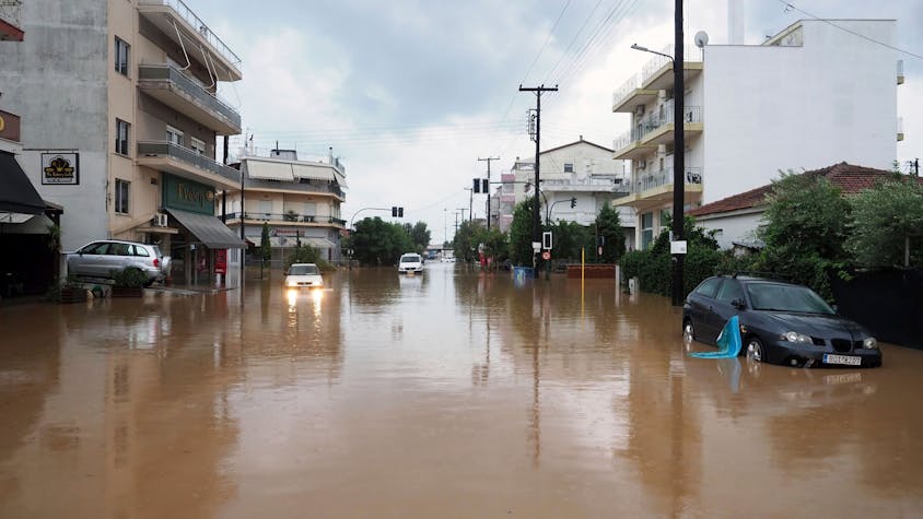 06.09.2023, Griechenland, Volos: Ein Autofahrer versucht, eine überflutete Straße nach einem Regensturm zu passieren.