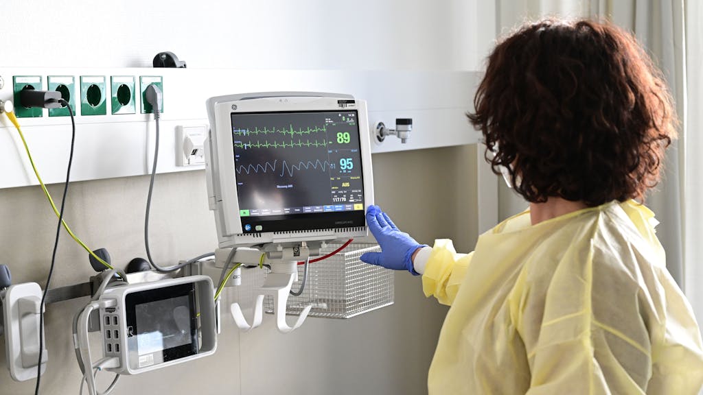 Eine Pflegerin schaut in einem Krankenzimmer im Klinikum Stuttgart auf einen Monitor einer Patientin, hier im Februar 2023.