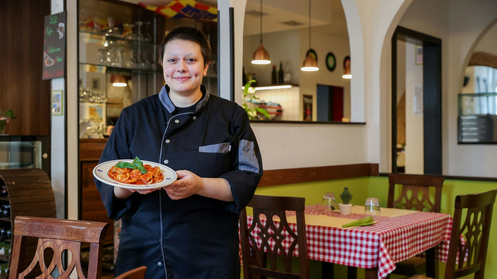Inhaberin Rebecca Chiriatti steht in ihrem Restaurant, mit einem Teller Pasta in der Hand.
