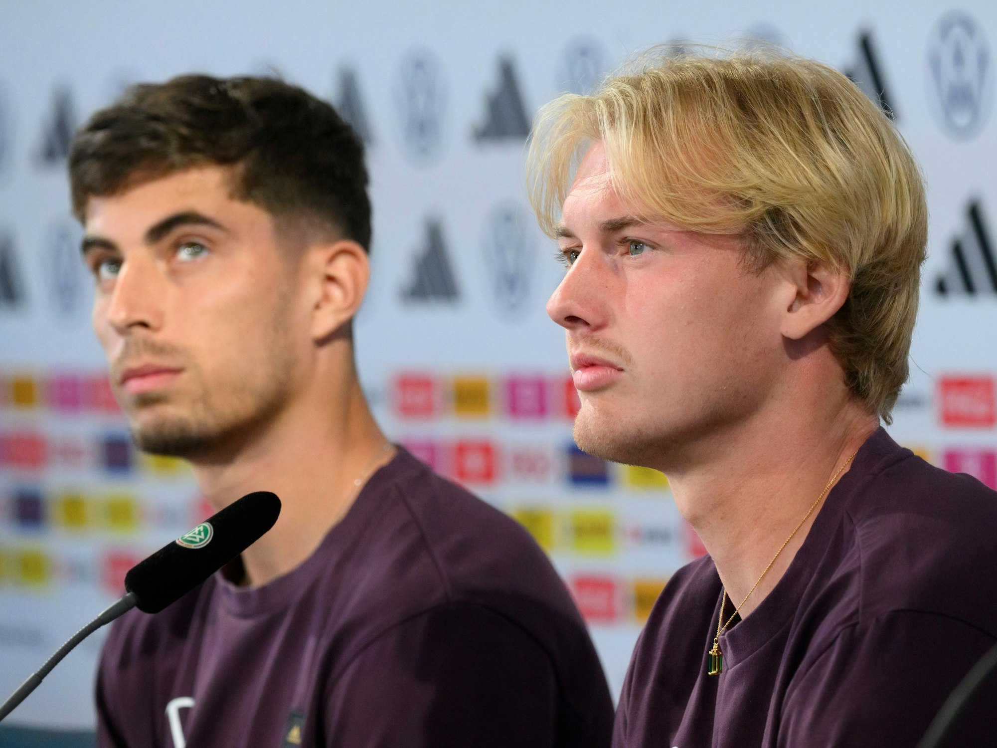 Die Nationalspieler Kai Havertz (l) und Julian Brandt sitzen bei der Pressekonferenz.