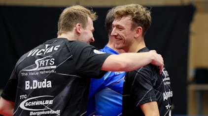 Tischtennis-Spieler Benedikt Duda umarmt seinen Mannschaftskollegen Adrien Rassenfosse.