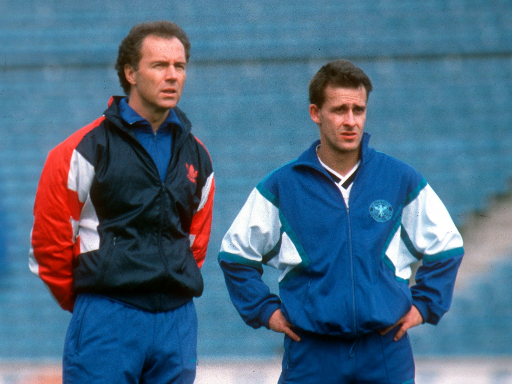 Bundestrainer Franz Beckenbauer steht neben Pierre Littbarski, der die Hände in den Hüften hat.