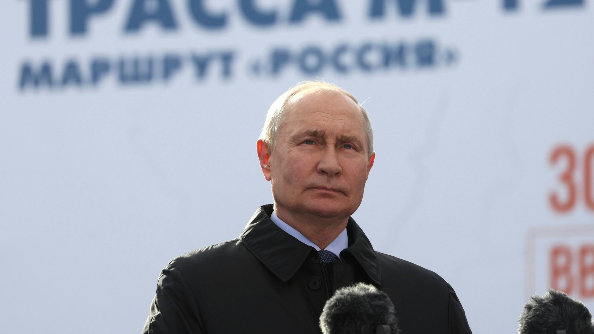 Wladimir Putin steht vor Mikrofonen und blickt in die Kameras.