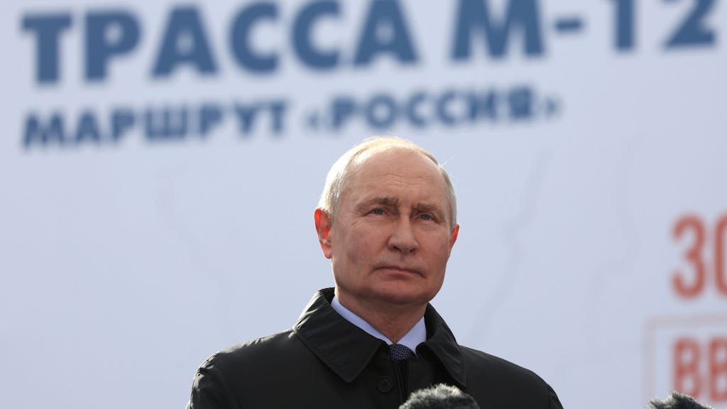 Wladimir Putin steht vor Mikrofonen und blickt in die Kameras.