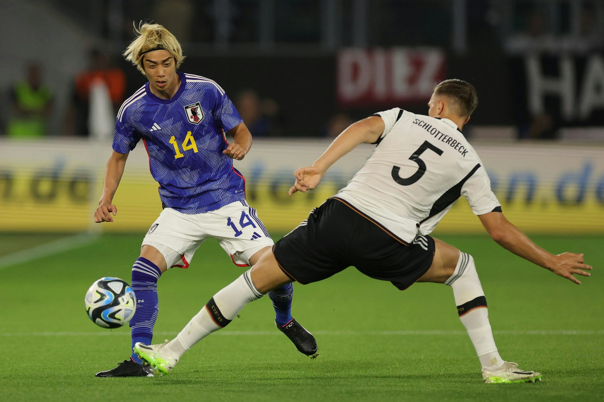 Japans Junya Ito (l) und Deutschlands Nico Schlotterbeck im Kampf um den Ball.