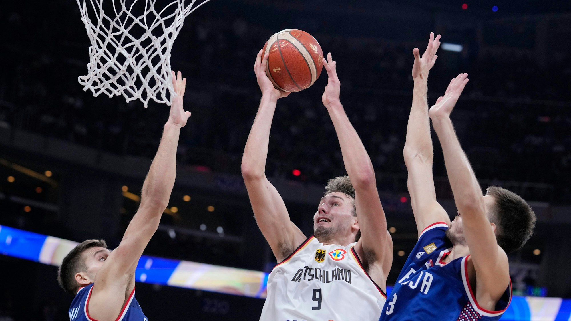 Germany guard Franz Wagner (9) shoots between Serbia guard Bogdan Bogdanovic (7) and Serbia c Filip Petrusev (3) during the championship game of the Basketball World Cup in Manila, Philippines, Sunday, Sept. 10, 2023. (AP Photo/Michael Conroy)