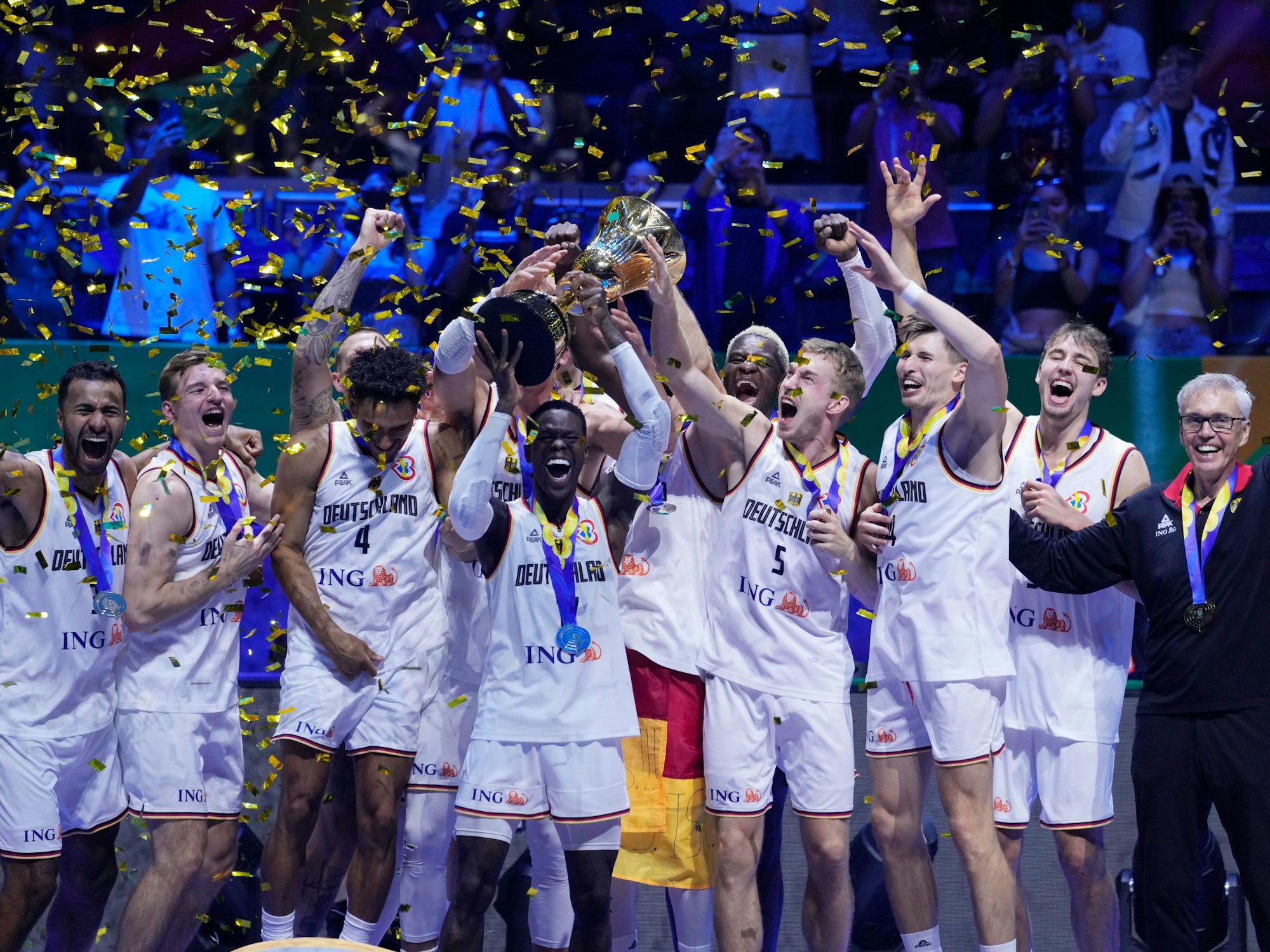 Die deutschen Basketball-Nationalspieler jubeln, haben die WM-Trophäe in ihrer Mitte.
